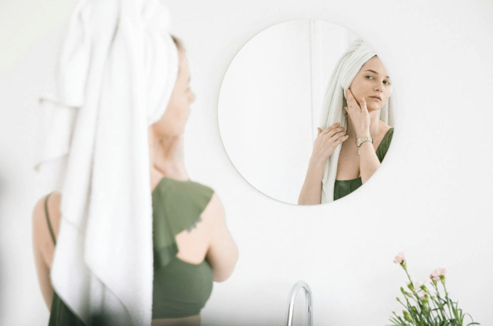 woman looking at skin in a mirror