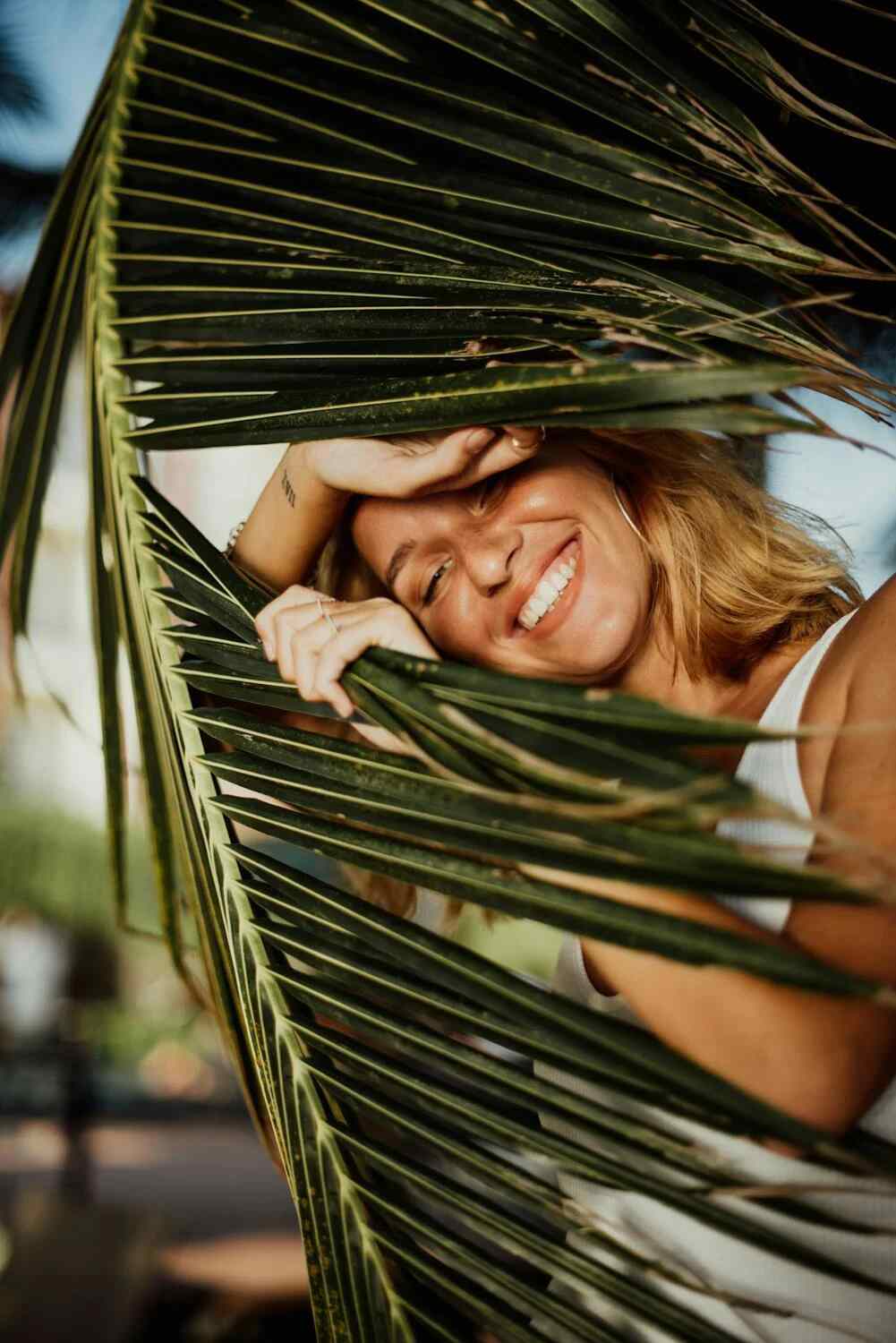 a woman smiling and holding a tropical plant