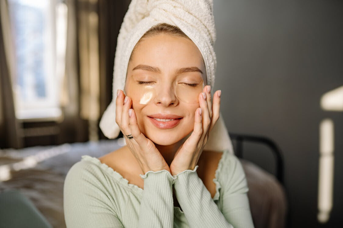 Woman with gel eye patches holding her face