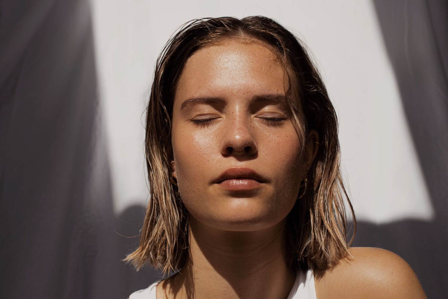 a woman with short brown hair and eyes closed