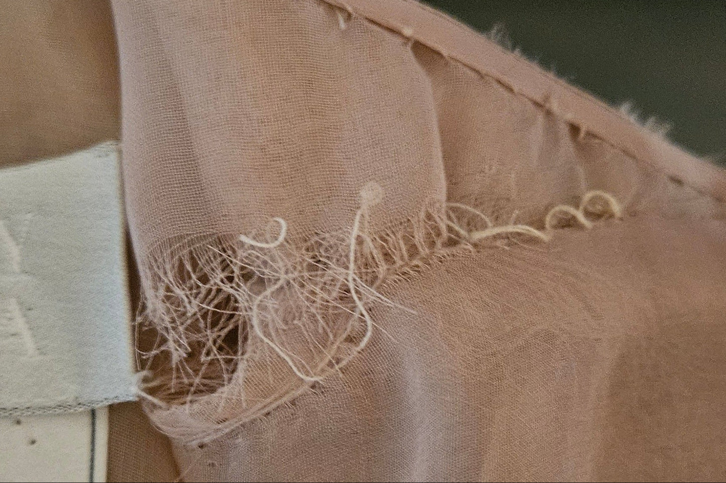 Close-up of beige fabric with a label, showing signs of wear.