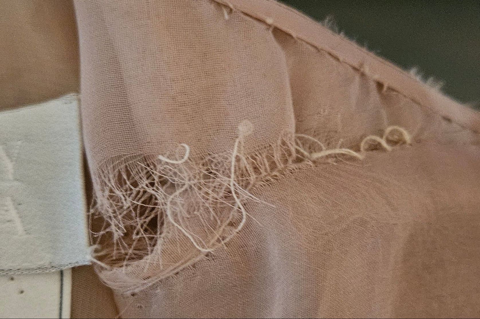 Close-up of beige fabric with a label, showing signs of wear.