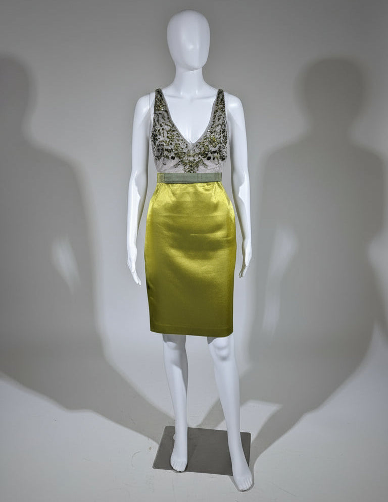 Mannequin wearing a green metallic skirt and black lace top against a neutral background
