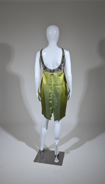 Mannequin wearing a green dress with embellishments on a gray background