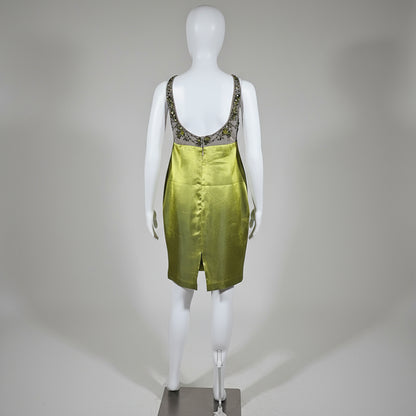 Mannequin wearing a green dress with a yellow curtain background
