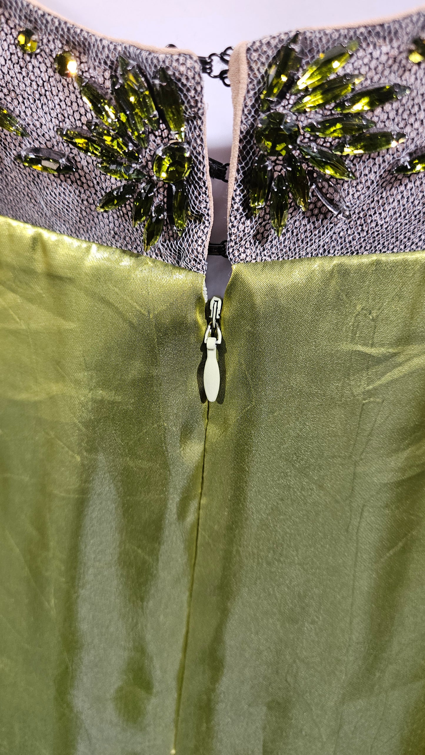 Close-up of a green fabric with a zipper and decorative elements on a textured background
