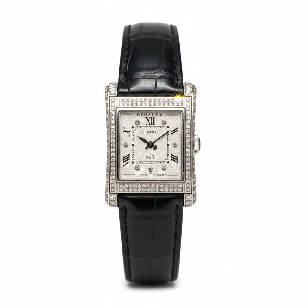 Luxury watch with black leather strap and diamond-studded case on a gray background