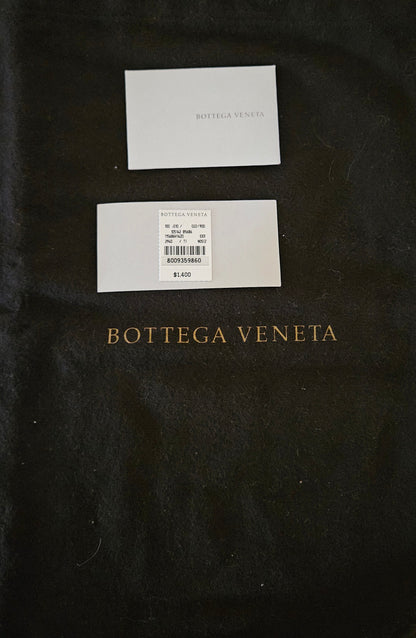 Two white cards on a black dust bag with 'Bottega Veneta' branding.