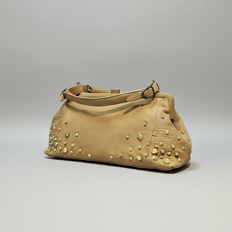 Beige handbag with gold studs on a gray background