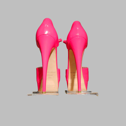 Pair of bright pink high-heeled shoes on clear stands against a dark background