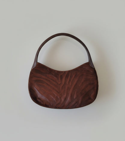 Brown textured handbag on a white surface