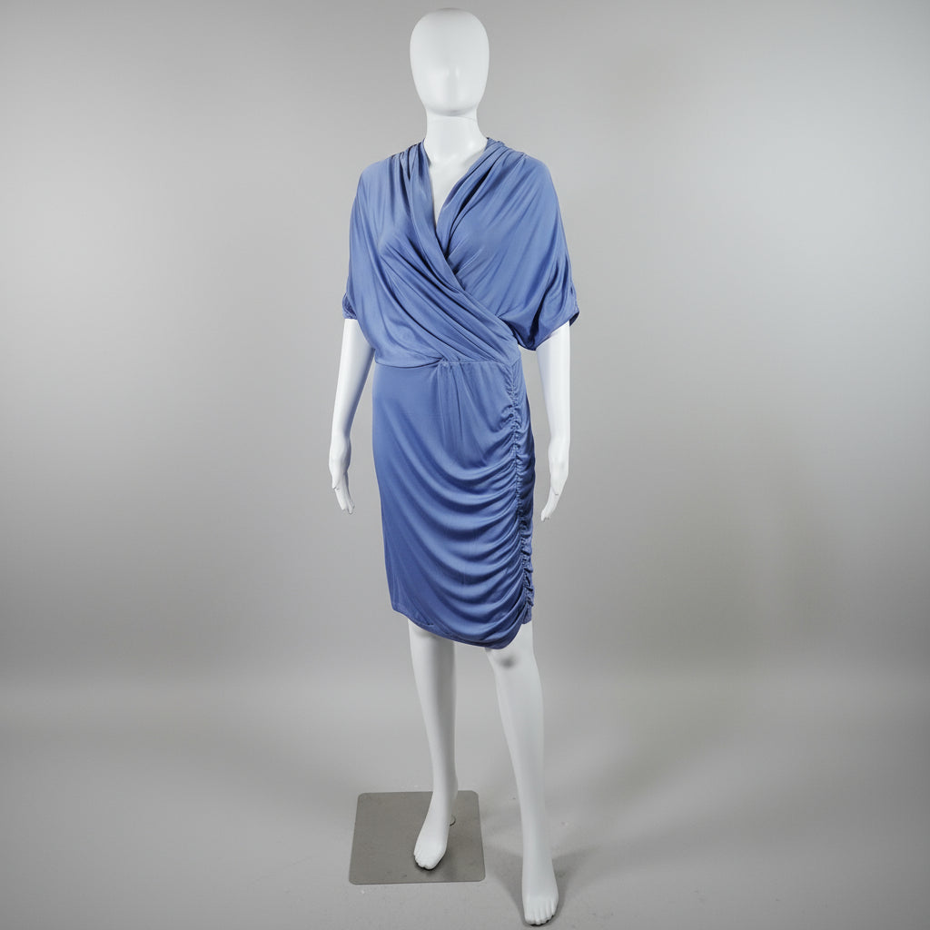 Mannequin wearing a blue dress against a yellow curtain backdrop