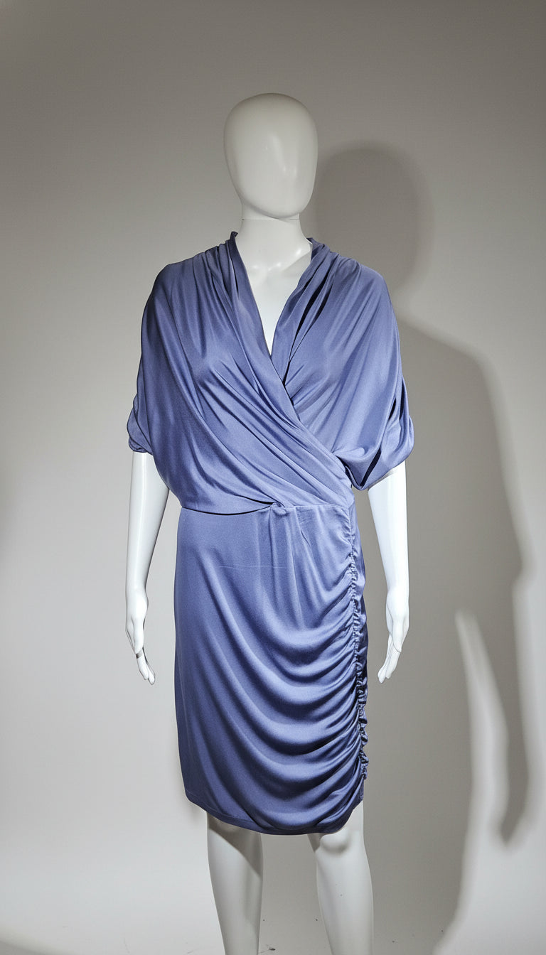Mannequin wearing a blue draped dress against a plain background