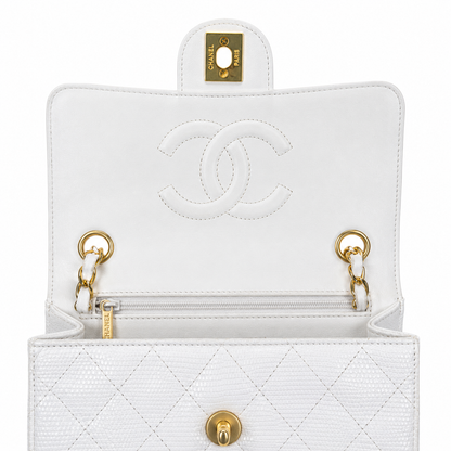 White quilted handbag with gold hardware and Chanel logo on a white background