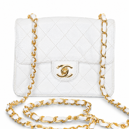 White quilted handbag with gold chain strap on a white background