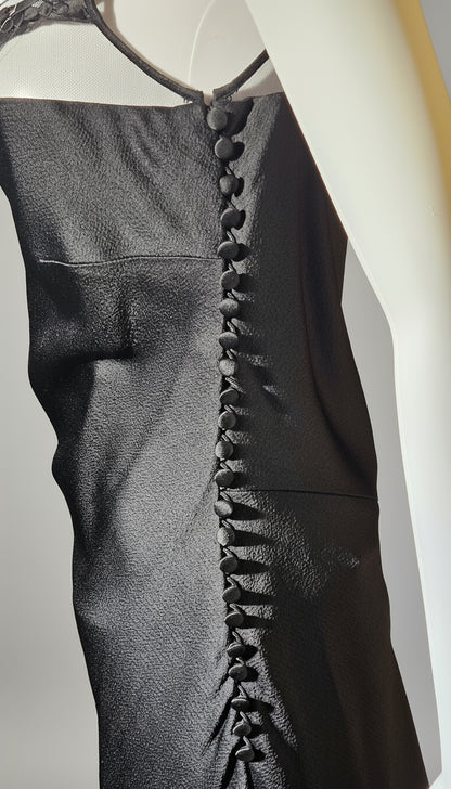 Black dress with button details on a mannequin against a neutral background