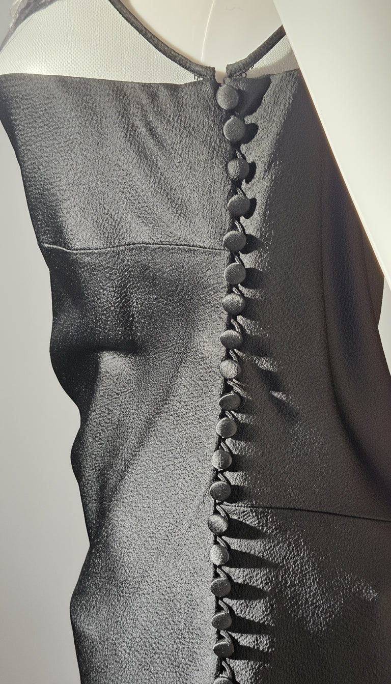 Close-up of a dark gray sleeveless top with button details on a light gray background