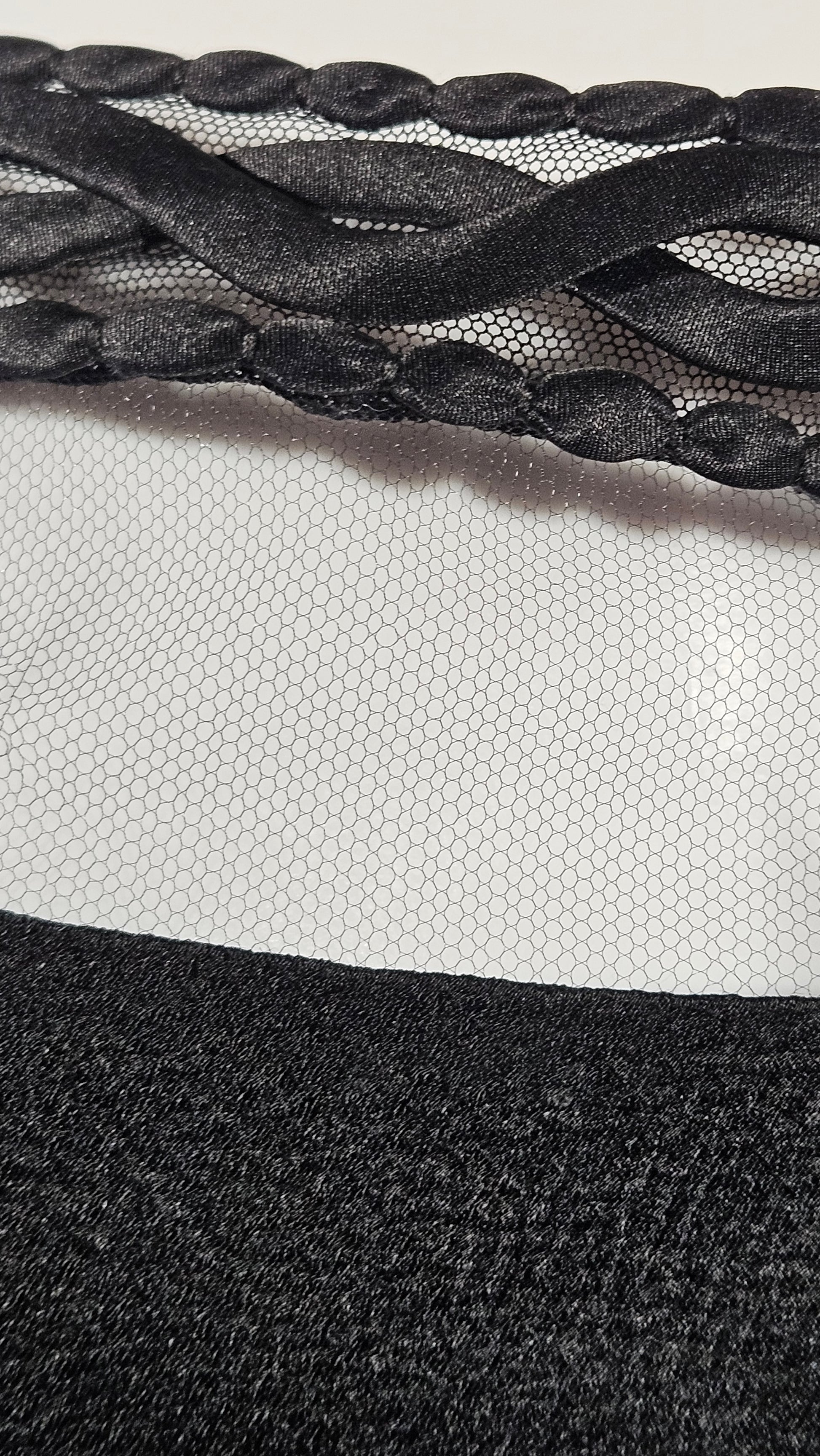 Close-up of a textured black fabric with braided pattern on a neutral background