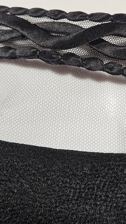 Close-up of a textured black fabric with braided pattern on a neutral background