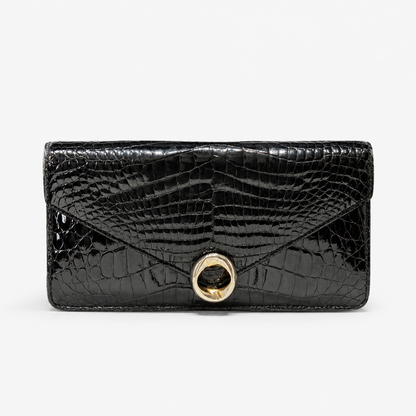 Black crocodile-patterned clutch handbag with a gold clasp on a white background