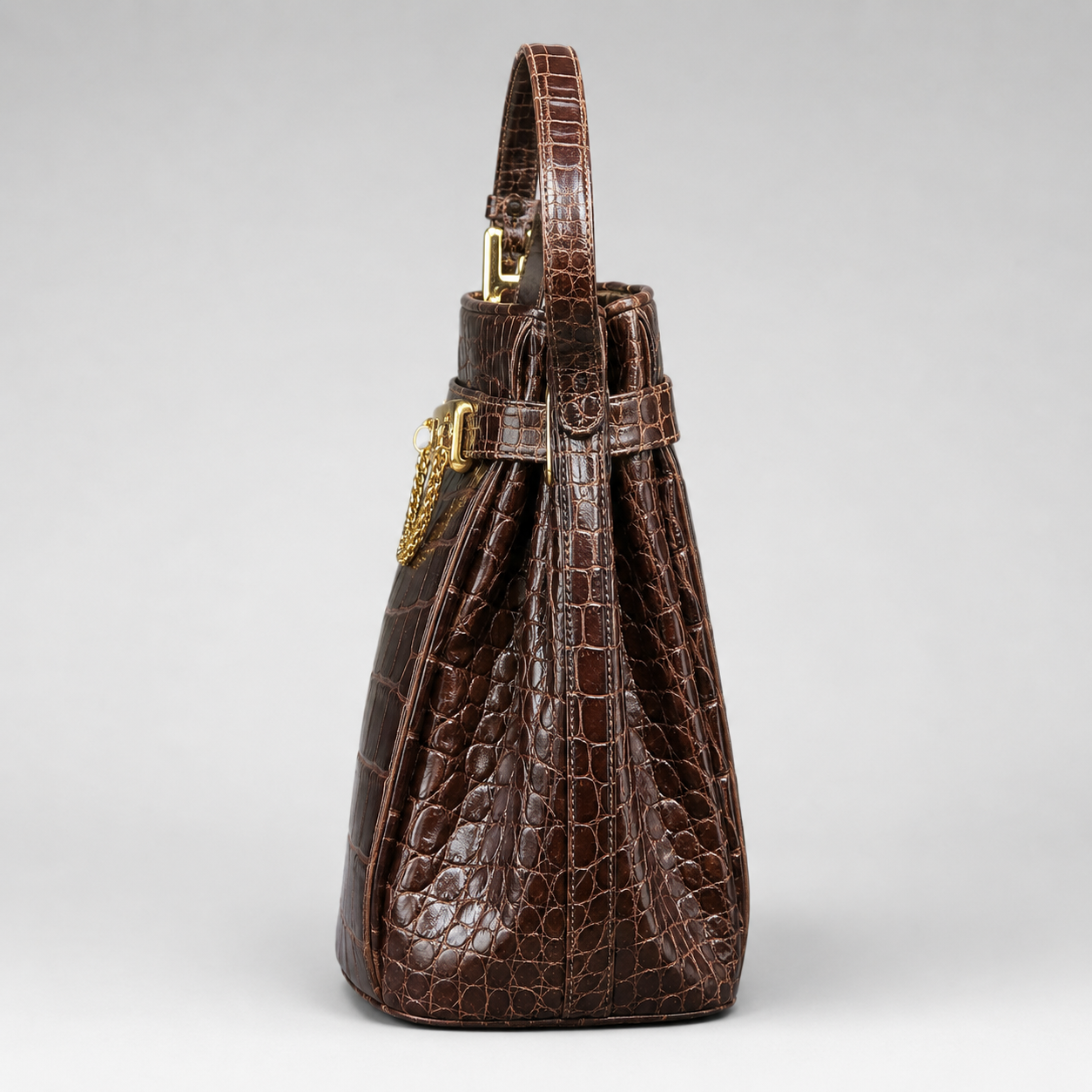 Brown textured handbag with a gold clasp on a light gray background