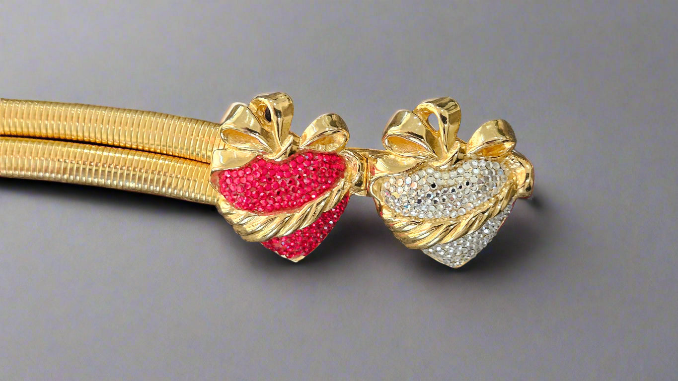 Gold belt with red and silver heart-shaped ends on a gray background