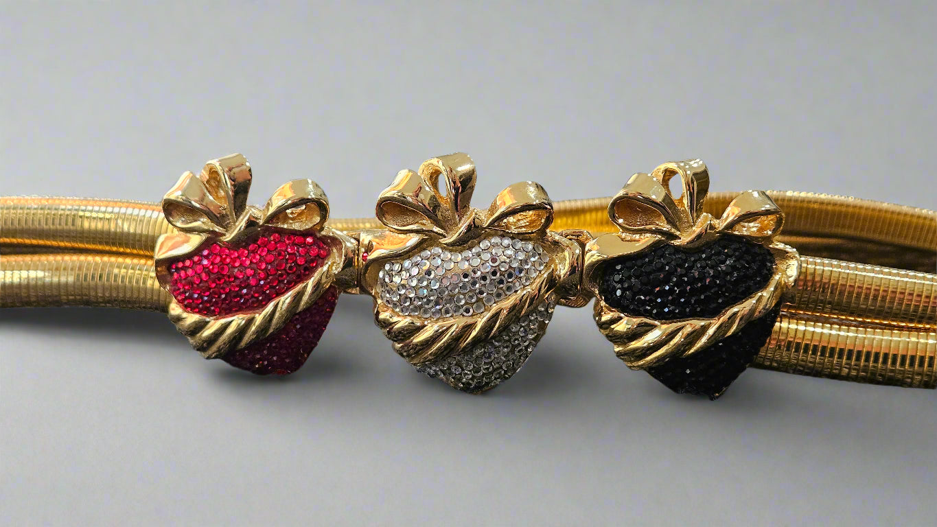 Gold belt with red, silver, and black heart-shaped gemstones on a light gray background