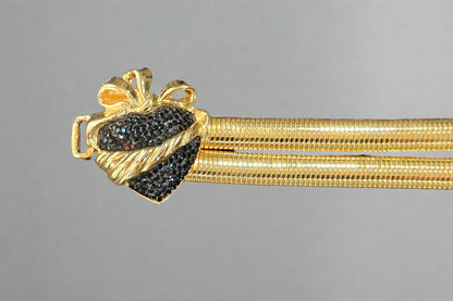 Gold heart buckle with black gemstones on a gray background