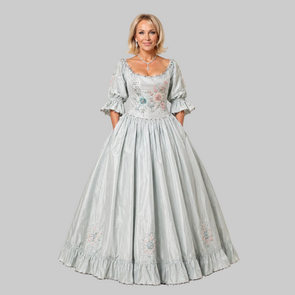 Woman wearing a light blue embroidered dress against a plain background