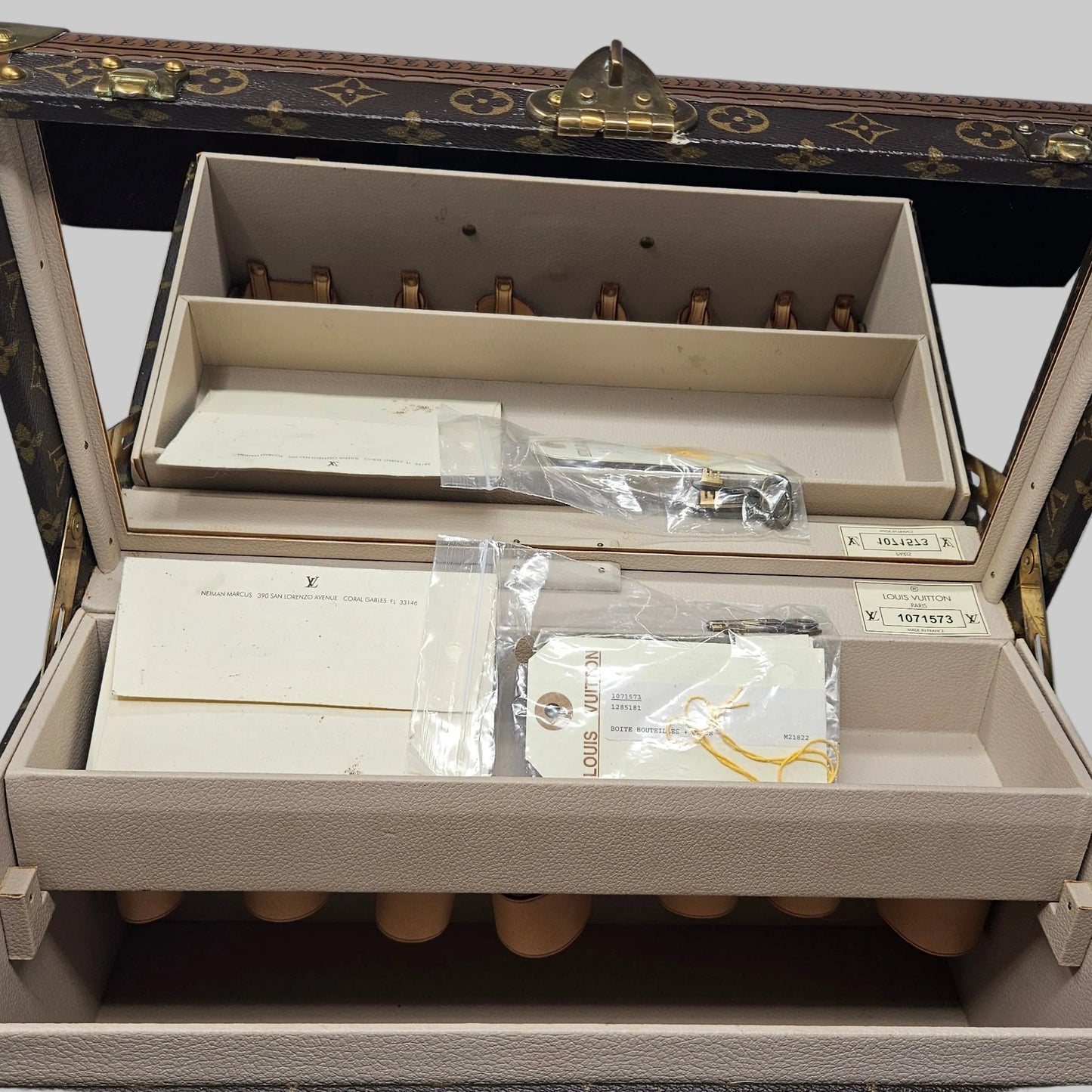 Open jewelry box with compartments and items inside on a white background