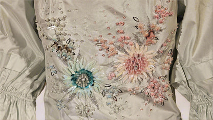 Elegant dress with floral embroidery and embellishments on a plain background