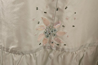 Close-up of a satin fabric with floral embroidery and bead details.