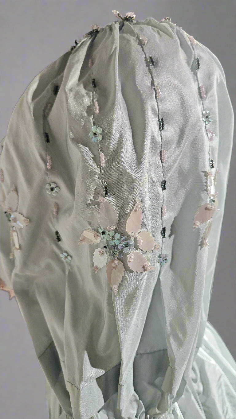 Light gray embroidered garment with floral details on a plain background