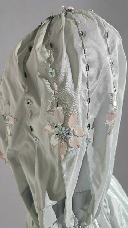 Light gray embroidered garment with floral details on a plain background