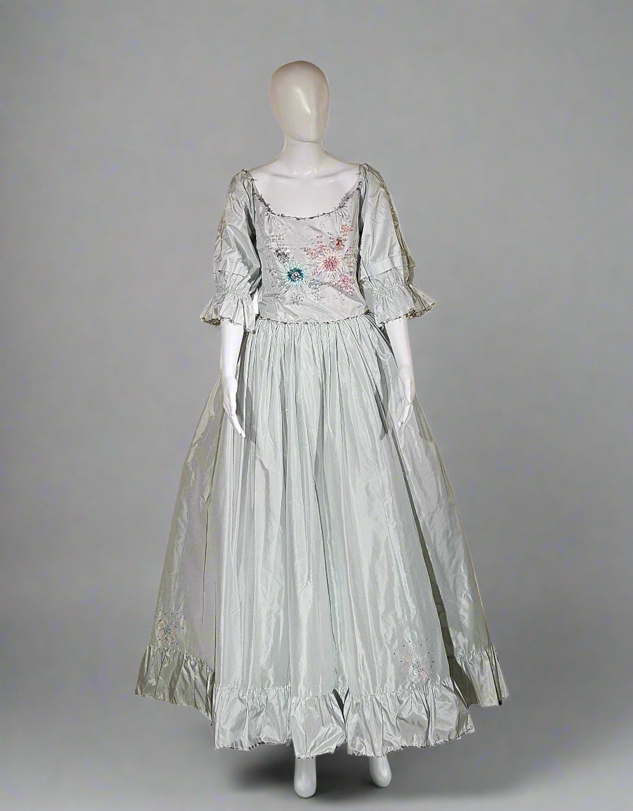 Mannequin wearing a light-colored dress with floral details in a store setting.