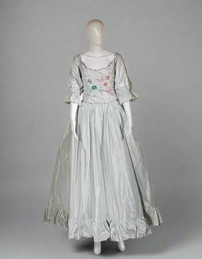 Mannequin wearing a light-colored dress with floral details in a store setting.