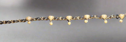 Gold chain belt with heart-shaped charms and small beads on a gray background