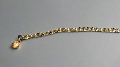 Gold chain belt with a heart-shaped charm on a gray background