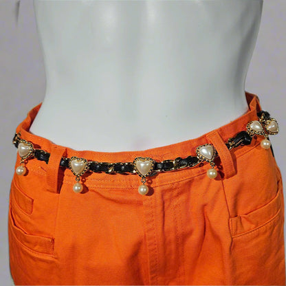 Orange pants with a decorative belt featuring pearls and heart-shaped charms on a plain background.