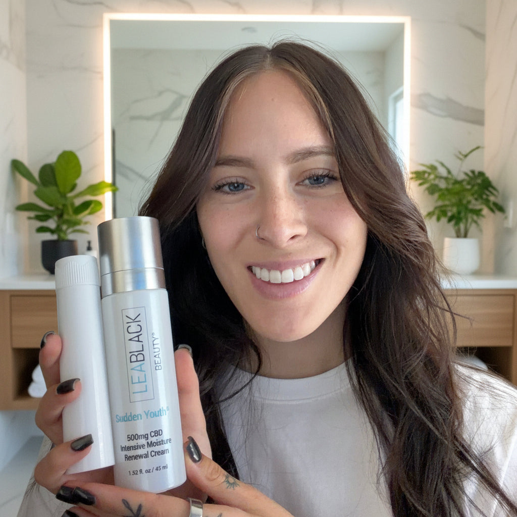 Woman holding a skincare product in a casual indoor setting.