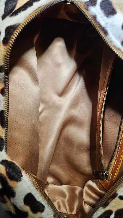 Leopard print handbag with a gold zipper, showing the interior.