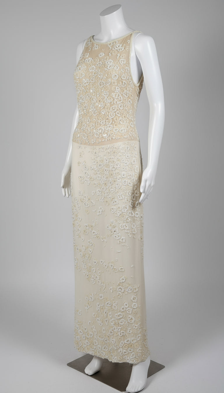 Mannequin wearing a long, elegant dress with floral patterns on a plain background