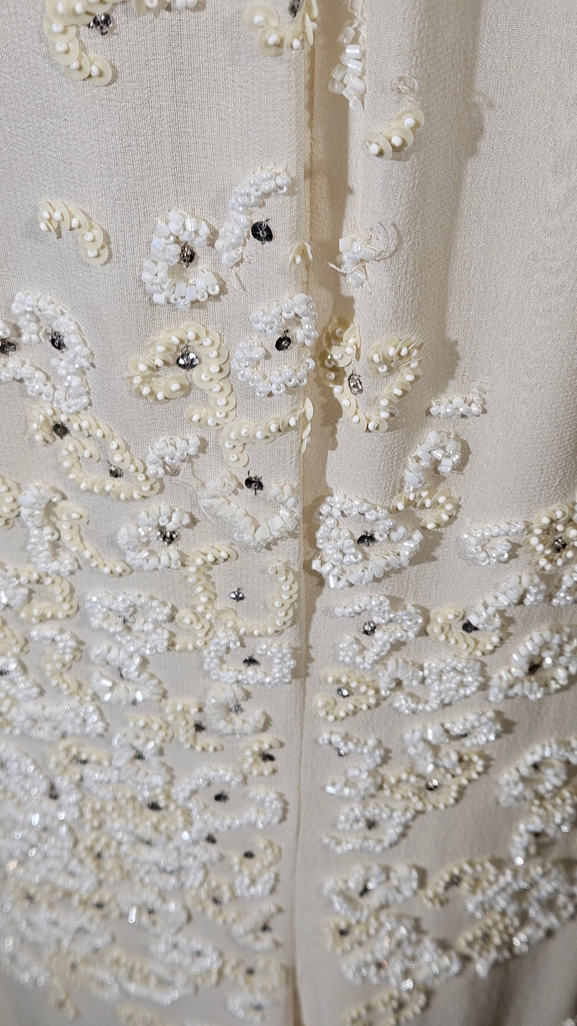 Close-up of a fabric with intricate beadwork and embroidery on a white background