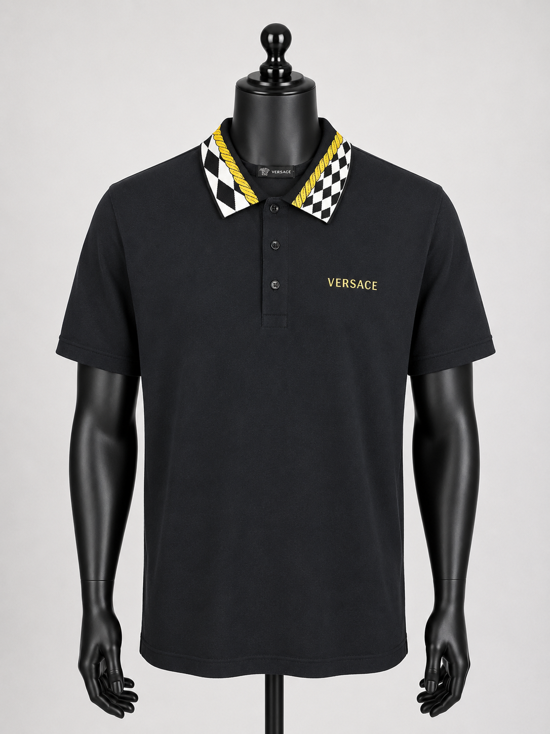 Black Versace polo shirt on a mannequin with a checkered collar against a gray background