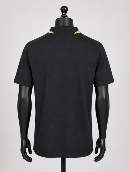 Black polo shirt on a mannequin with yellow accents against a gray background