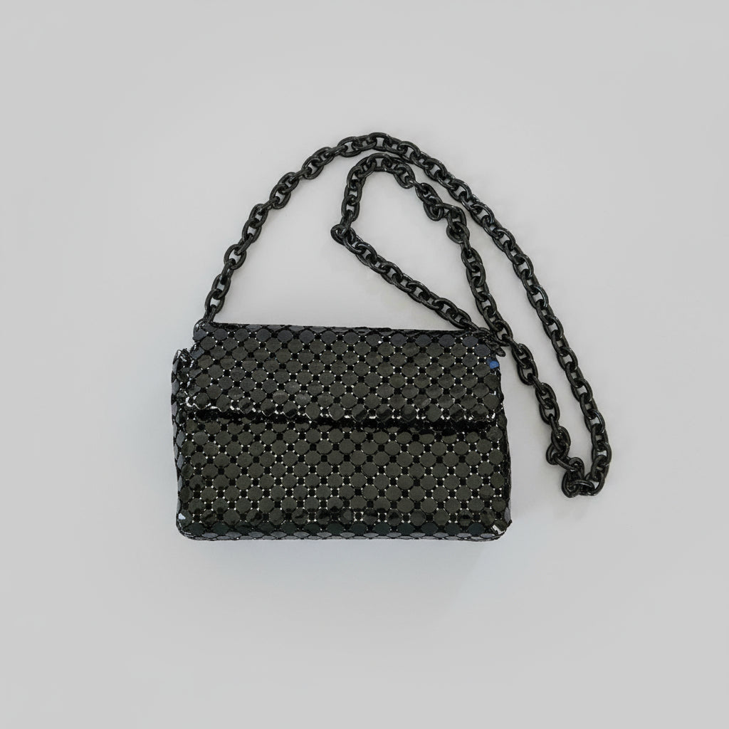 Black textured handbag with chain strap on a light gray background