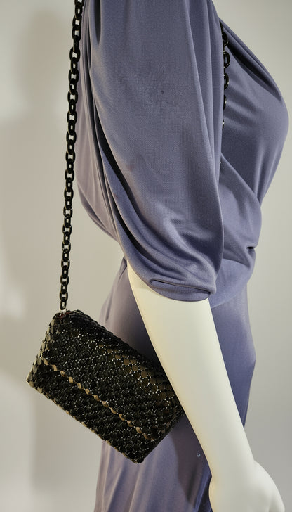 Black beaded handbag on a mannequin with a light purple garment in the background