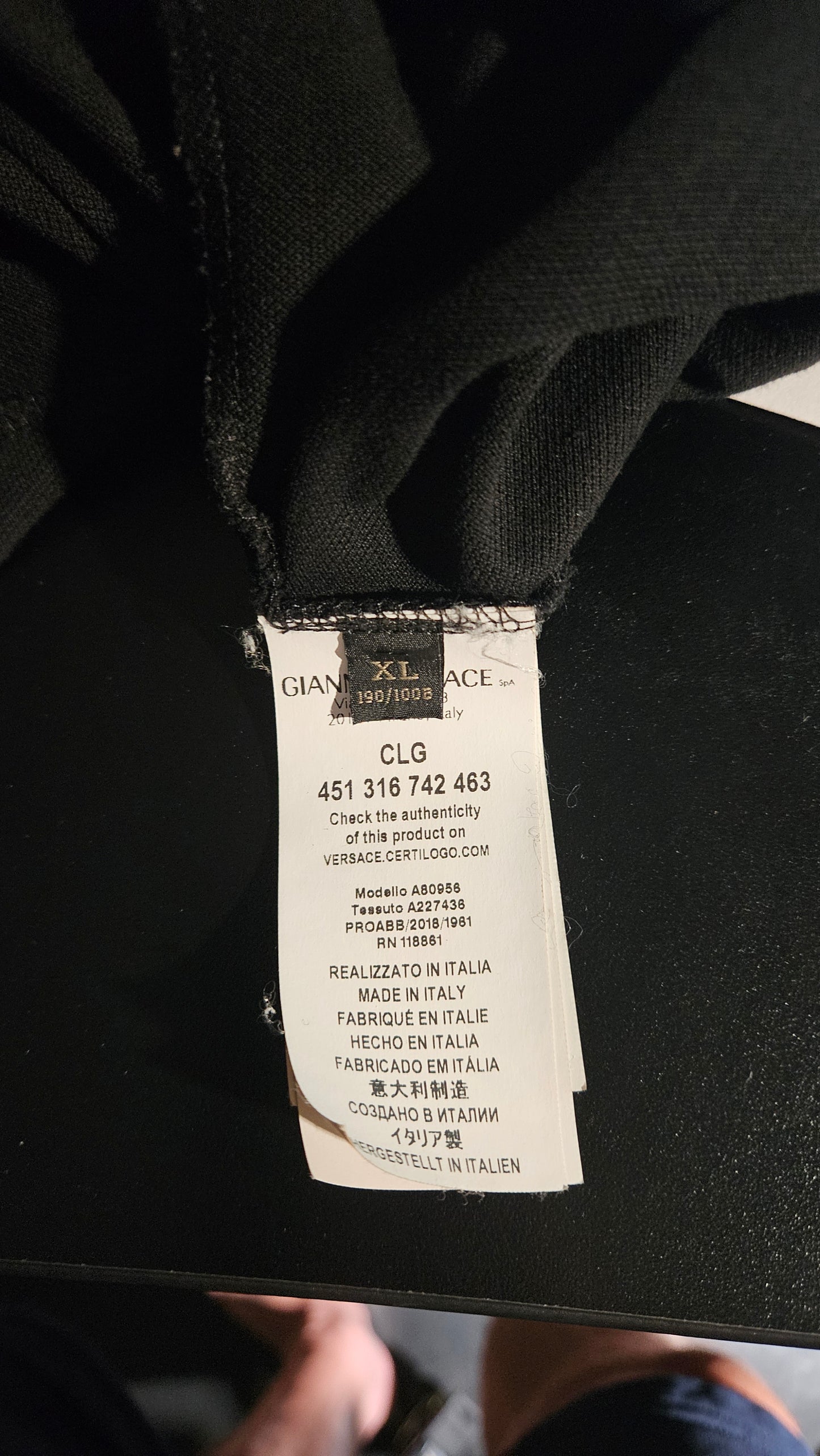 Clothing tag on a black garment with visible text and numbers.